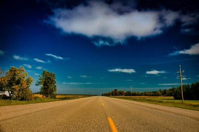 Road amidst field against sky