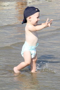 Full length of shirtless boy walking in sea