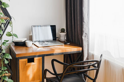 Modern workplace at home with laptop on wooden table at the room full of sunlight