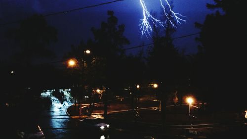 Illuminated street light against sky at night