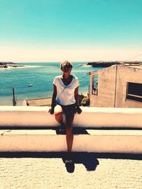 Woman standing against sea and sky during sunny day