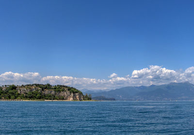 Scenic view of sea and mountains against blue sky