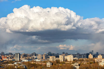 A beautiful spring cityscape with a white cloud hovering over the city in the blue sky.