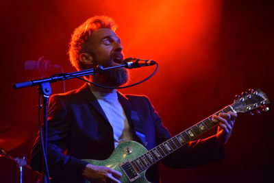 Low angle view of man playing guitar while singing on stage