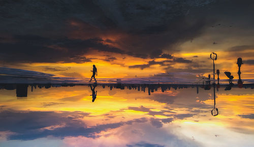 Silhouette man by sea against sky during sunset