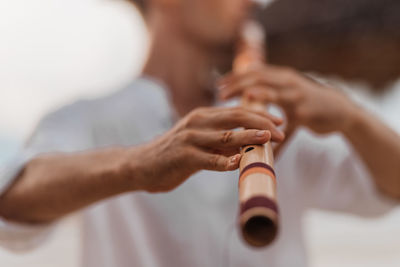 Man playing wind instrument on the beach at sunrise