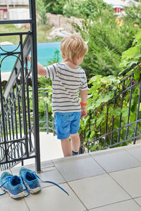 Rear view of boy looking at railing