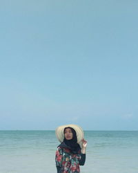 Portrait of young woman standing in sea against sky