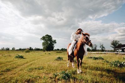 Young woman riding horse on field