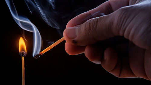 Close-up of hand holding burning candle