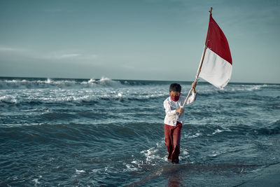 Full length of man standing in sea against sky