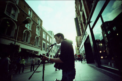 Side view of man walking on street against buildings in city