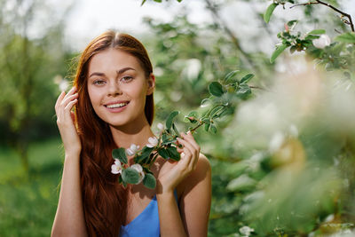 Portrait of smiling young woman standing by plants