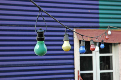 Close-up of light bulbs hanging against house