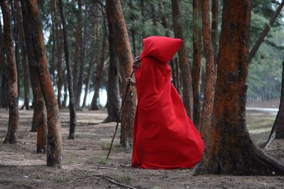 Woman in red costume walking amidst trees in forest