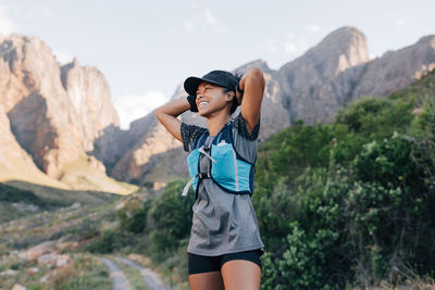 Portrait of young woman standing against mountain