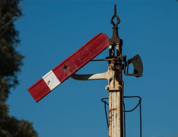 Low angle view of railway signal against clear blue sky