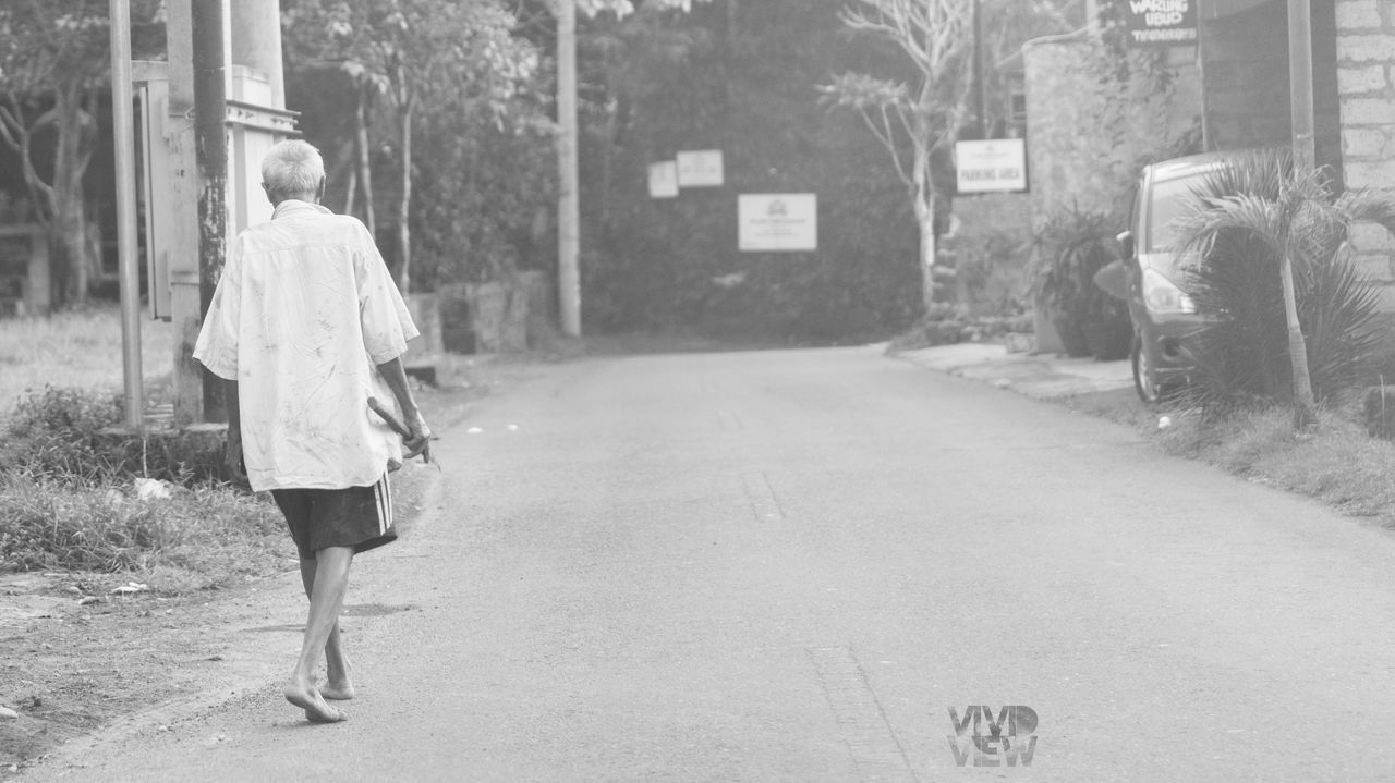REAR VIEW OF WOMAN WALKING ON STREET