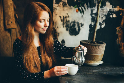 Portrait of young woman holding coffee on table