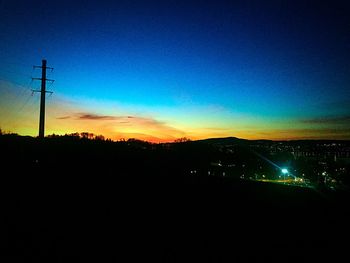 Silhouette of electricity pylon at dusk