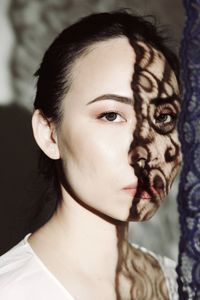 Close-up portrait of young woman with shadow on face