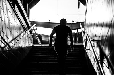 Rear view of man walking on staircase