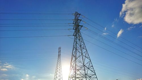 Low angle view of electricity pylon against blue sky