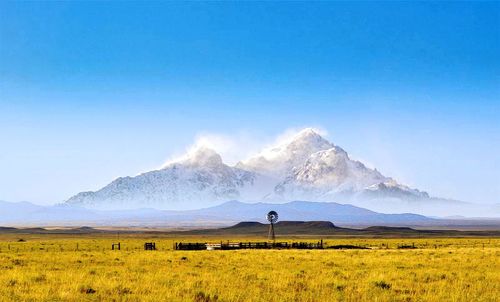 Scenic view of field and mountains against blue sky