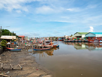 Boats moored in sea by houses against sky