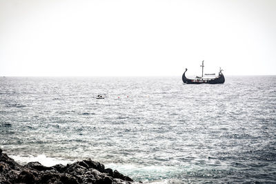 Boat sailing in sea against clear sky
