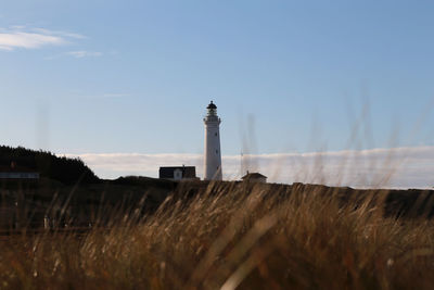 Lighthouse on field against sky