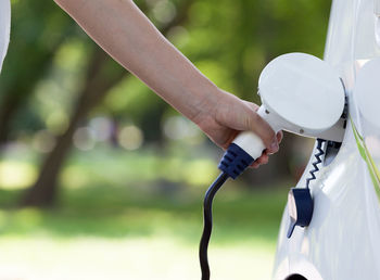 Cropped hand charging car at station