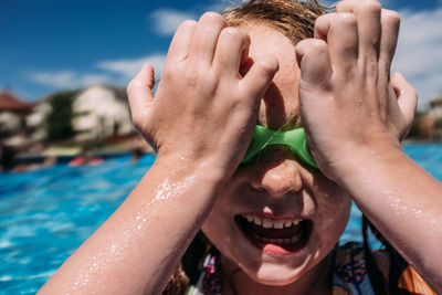 Close up of young child pushing goggles on to face at pool