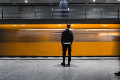 Rear view of man standing against train at subway station