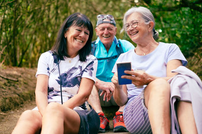 Portrait of smiling friends sitting on field