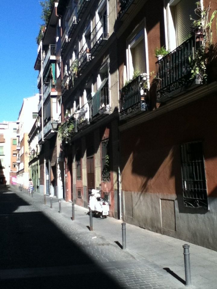 building exterior, architecture, built structure, residential building, residential structure, street, city, house, window, building, sunlight, balcony, day, city life, shadow, outdoors, incidental people, alley, sidewalk, low angle view