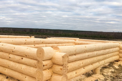 Stack of logs on field against sky