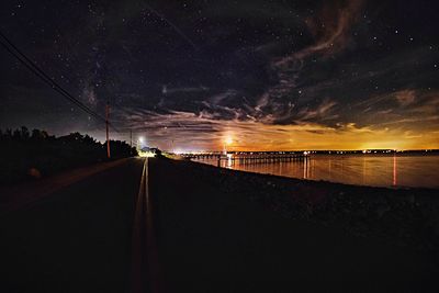 Illuminated walkway against sky at night