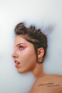 Close-up portrait of young woman against white background