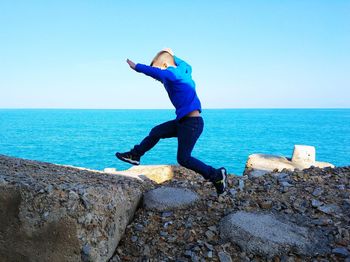 Full length of woman standing on rock against sea