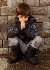 Full length of boy sitting against wall