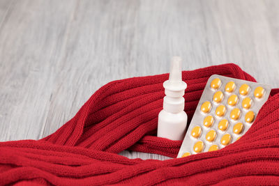 High angle view of blister pack with nasal spray and scarf on table