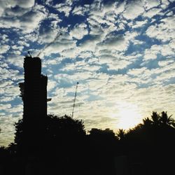 Low angle view of silhouette trees against cloudy sky