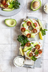 Bagels sandwich with cream cheese, cottage cheese, avocado, tomatoes, cucumbers and salad leaves