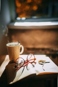 Coffee cup and book on table at home