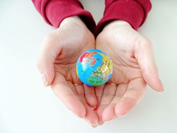 Close-up of hand holding crystal ball over white background