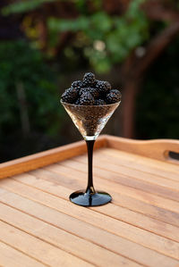 Fresh sweet blackberry in glass on a wooden table, rustic background, selective focus