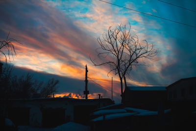 Silhouette tree and buildings against sky during sunset