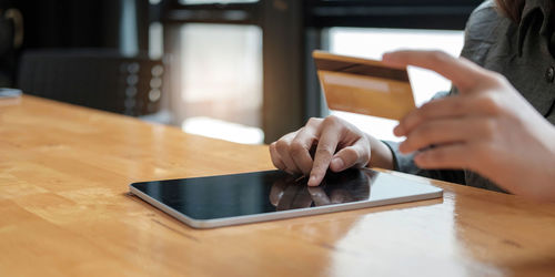 Midsection of man using mobile phone on table