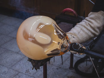 Man artists hands working on a blown glass piece. shaping glass bowl with wet tool. kunratice